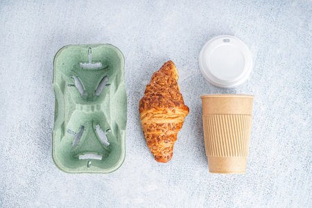 Paper cup, cap, holder and tasty croissant on light backgroundの写真素材