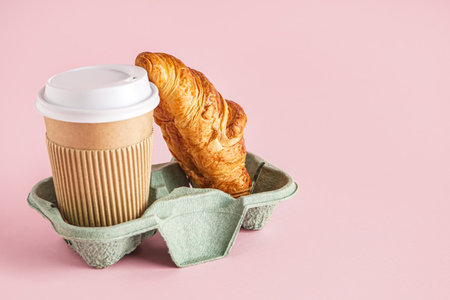 Holder with paper cup and tasty croissant on pink background
