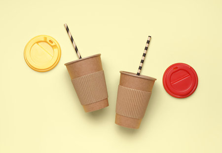 Paper cups with straws and caps on yellow backgroundの写真素材