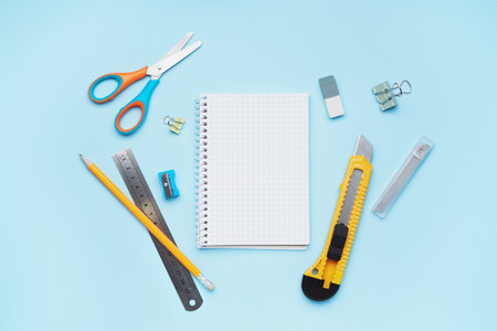 Utility knife with stationery on blue background