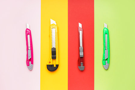 Utility knives on color background