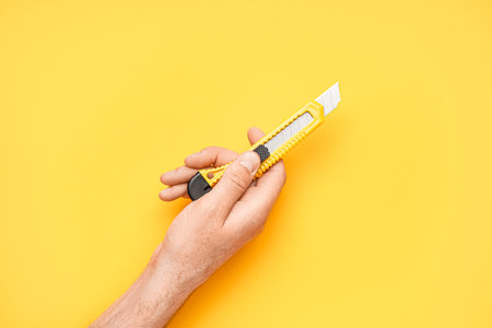 Man with utility knife on yellow backgroundの写真素材