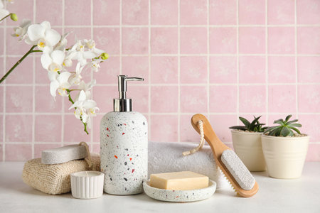 Set of bath supplies and orchid flower on table against color tile