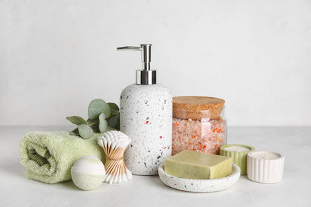 Set of different bath supplies with candles on light background