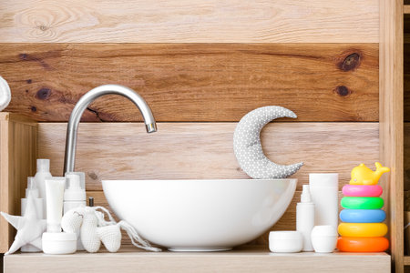 Table with sink, toys and baby bath accessories near wooden wallの写真素材