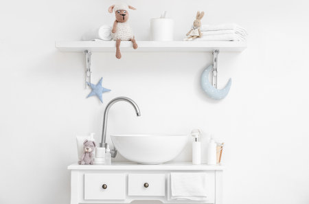 Modern sink, cute toys and bath accessories for children near white wallの写真素材