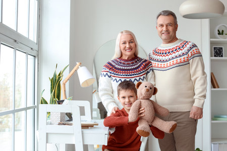 Little boy with toy and his grandparents in warm sweaters at homeの写真素材