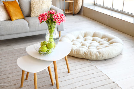 Basket with fresh apples and vase with tulips on table in roomの写真素材
