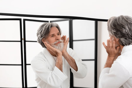 Mature man taking care of his beard and mustache in bathroomの写真素材