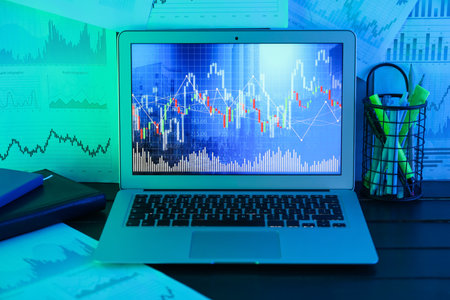 Laptop with diagram of exchange rate on table in office