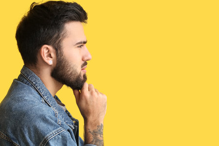 Profile of pensive bearded man on yellow background