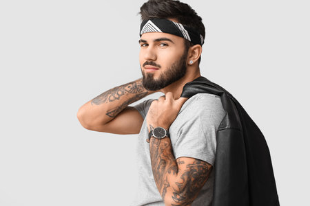 Bearded man holding jacket over shoulder on light backgroundの写真素材