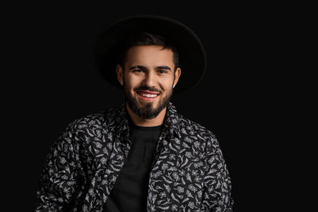 Fashionable bearded man in stylish hat on dark background