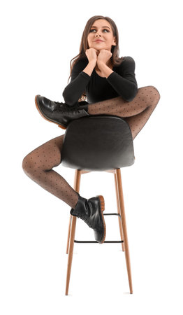 Beautiful young woman in black tights sitting on chair against white backgroundの写真素材