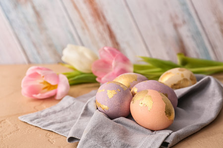 Beautiful Easter eggs and tulip flowers on table, closeup