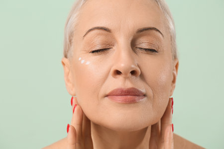 Mature blonde woman with healthy skin on green background, closeupの写真素材
