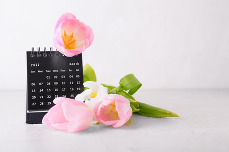Calendar and flowers for International Women's Day celebration on light backgroundの写真素材