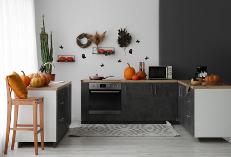 Interior of modern kitchen decorated for Halloween with pumpkins and black countersの写真素材