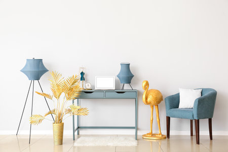 Interior of room with comfortable workplace, armchair and golden flamingo near white wallの写真素材