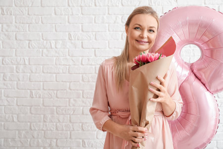 Woman with bouquet of tulips on white brick wall background. International Women's Day celebration