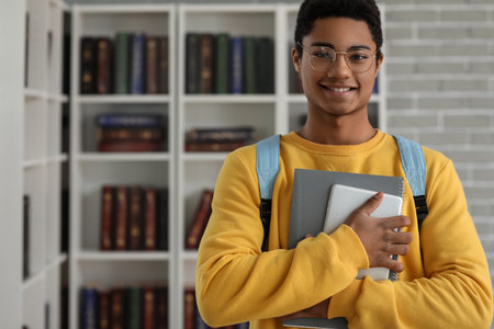 Male African-American student with tablet computer and notebook in libraryの写真素材