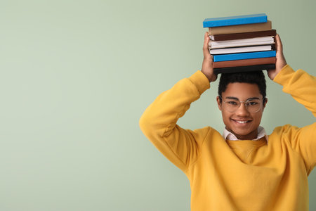 Male African-American student with stack of books on color backgroundの写真素材