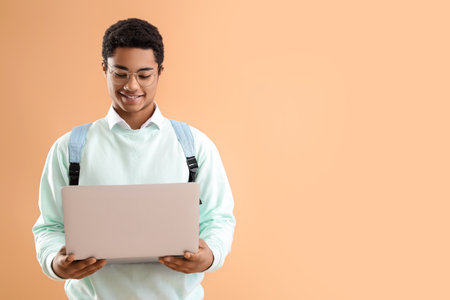 Male African-American student with modern laptop on color backgroundの写真素材