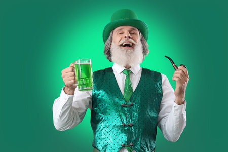 Senior man with smoking pipe and glass of beer on green background. St. Patrick's Day celebration