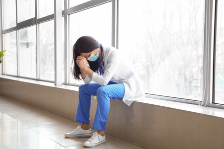 Worried female doctor with medical mask in hall of clinicの写真素材
