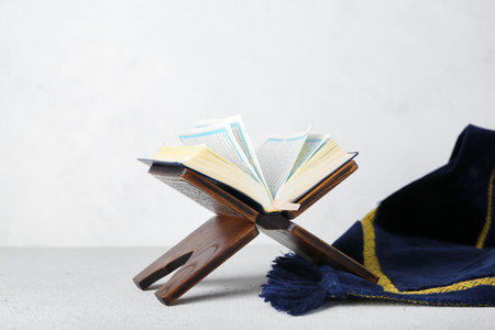Rehal with Koran and Muslim prayer mat on light background