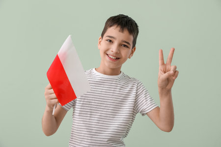 Happy little boy with flag of Poland showing victory gesture on green backgroundの写真素材