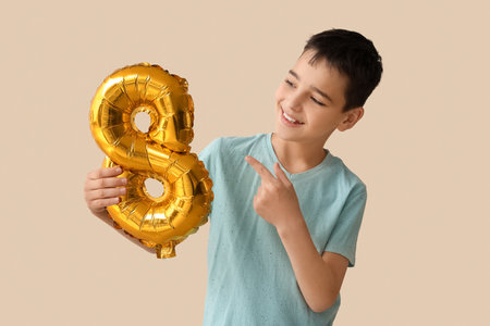 Little boy pointing at balloon in shape of figure 8 on beige background. International Women's Dayの写真素材