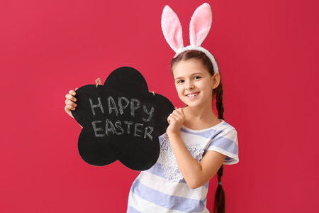 Funny little girl with bunny ears and board with text HAPPY EASTER on red background