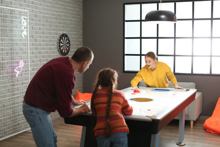 Family playing air hockey indoors