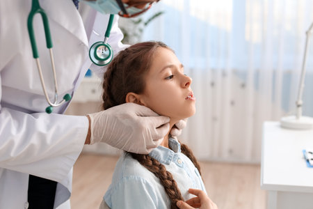 Doctor examining little girl's neck in clinicの写真素材