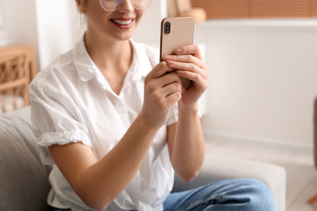 Pretty young woman using mobile phone at homeの写真素材