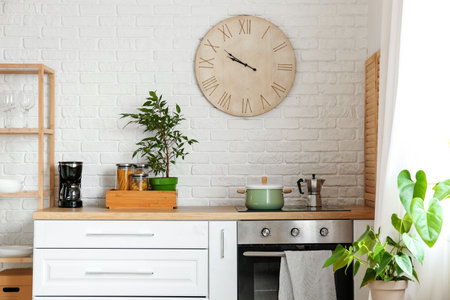 Big clock hanging on white brick wall in kitchenの写真素材