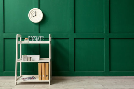 Shelving unit with decor and clock hanging on green wallの写真素材