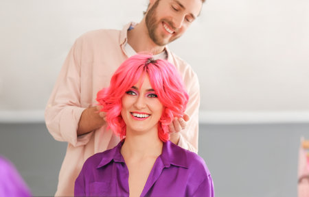 Male stylist doing hair of young woman in beauty salonの写真素材