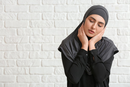 Beautiful Muslim woman on white brick backgroundの写真素材