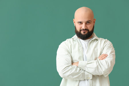 Portrait of handsome bald man with crossed arms on green backgroundの写真素材