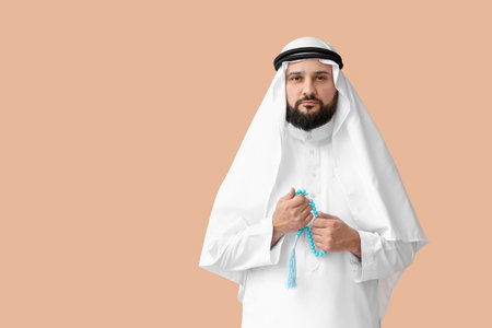 Muslim man with prayer beads on color background