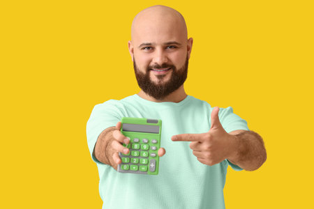 Bald man with calculator on yellow backgroundの写真素材