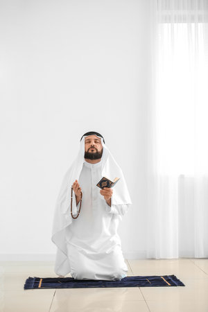 Muslim man with Koran and beads praying at homeの写真素材