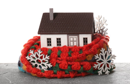 House model with scarf and snowflakes on table against white background. heating conceptの写真素材