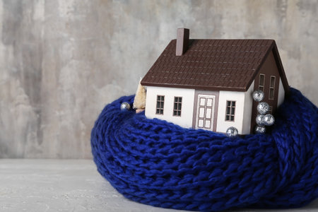 House model with scarf and decor on table against grunge background. heating conceptの写真素材