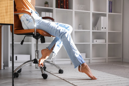 Barefoot legs of young woman sitting in officeの写真素材