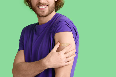 Young man with applied medical patch on color background