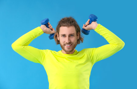 Sporty man with dumbbells on blue background