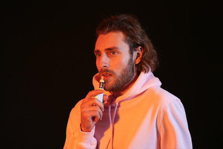 Vaping young man on black backgroundの写真素材